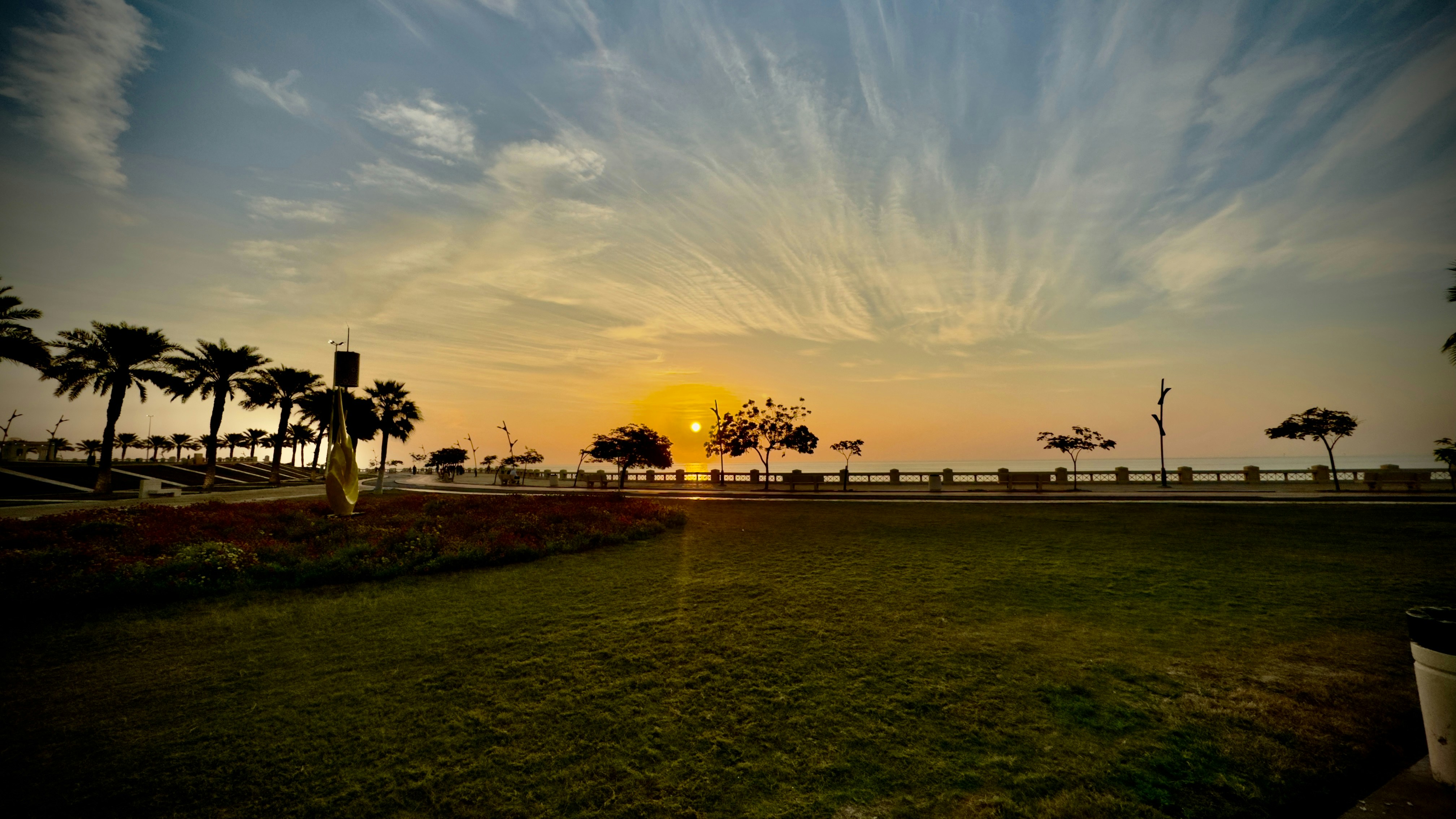 the sun is setting over a park with palm trees
