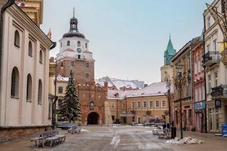 a snowy street with benches and a church in the background