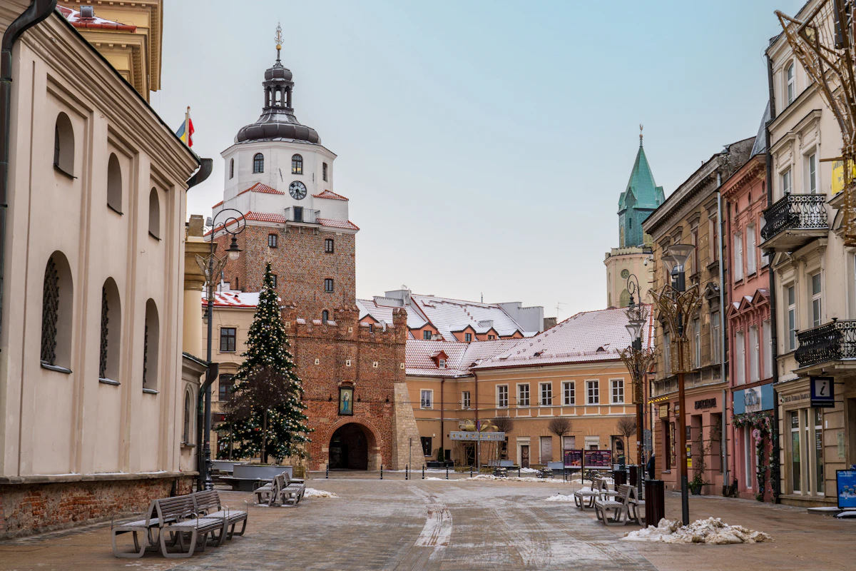 Ośnieżona uliczka z ławkami i kościołem w tle