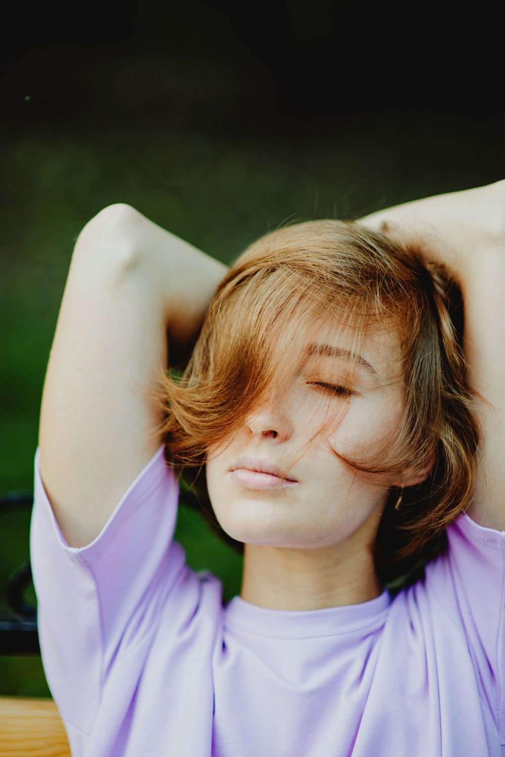 a woman with her eyes closed sitting on a bench