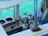 A collection of scuba diving tanks is arranged on a boat near a turquoise body of water. A mobile phone is placed on a wooden surface, and a set of clothes hangers are visible. The scene includes elements like metal bars and a platform with blue cushioning.