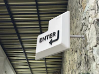 a white sign hanging from the side of a stone building