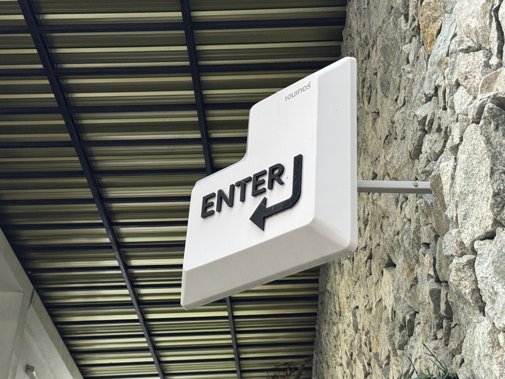 a white sign hanging from the side of a stone building