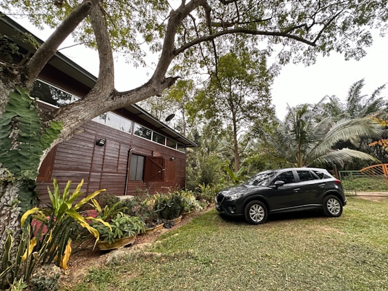 A cozy modern rental home with a boat and car parked outside, surrounded by tropical greenery.