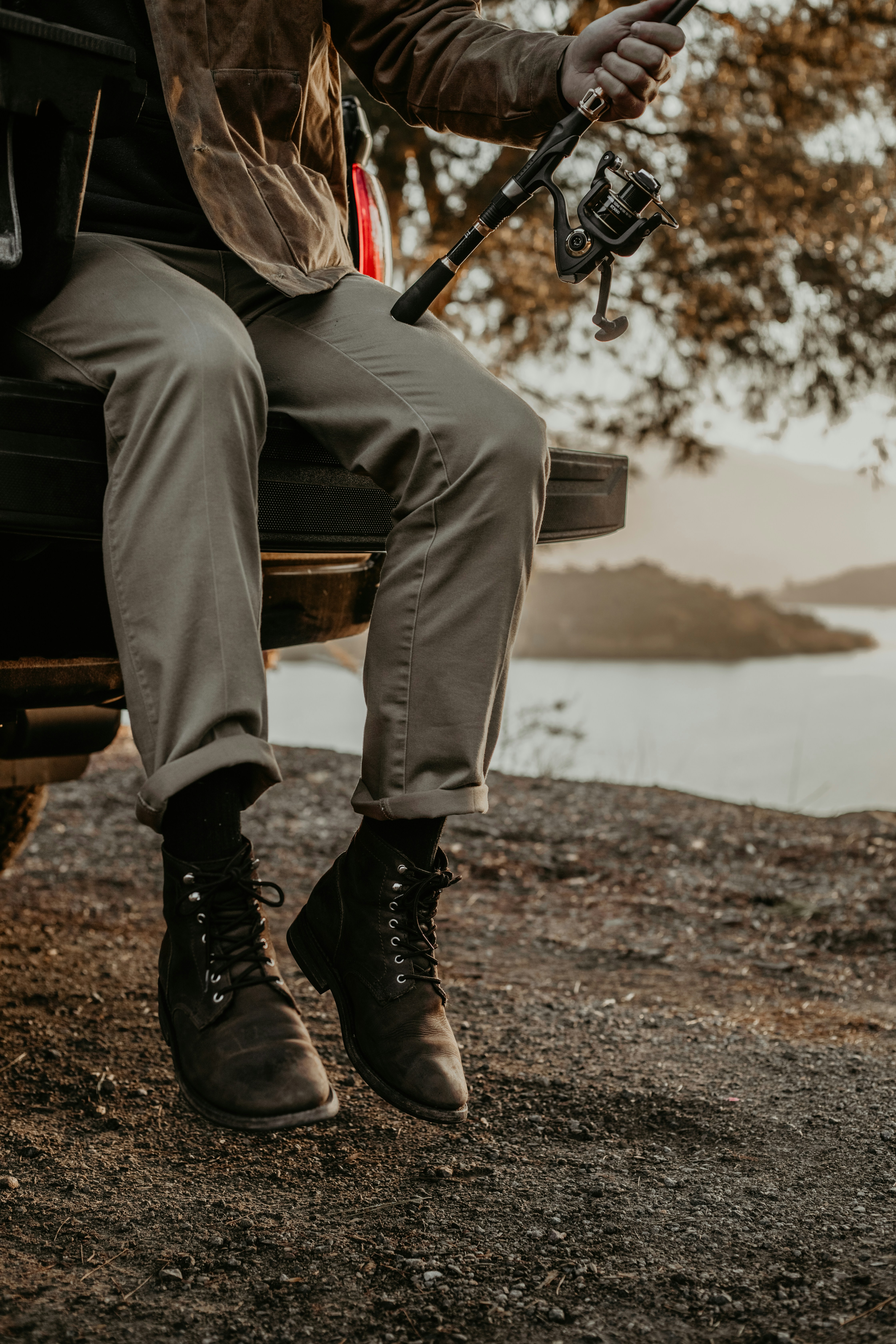 a man sitting on the back of a truck holding a fishing rod