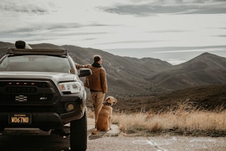 a man standing next to a truck with a dog