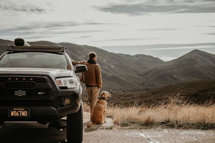 a man standing next to a truck with a dog