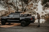 A rugged pickup truck parked near a marsh, with a hat hanging from the side mirror.