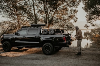 A rugged outdoor scene with a father and son packing hunting gear beside a pickup truck at dawn.