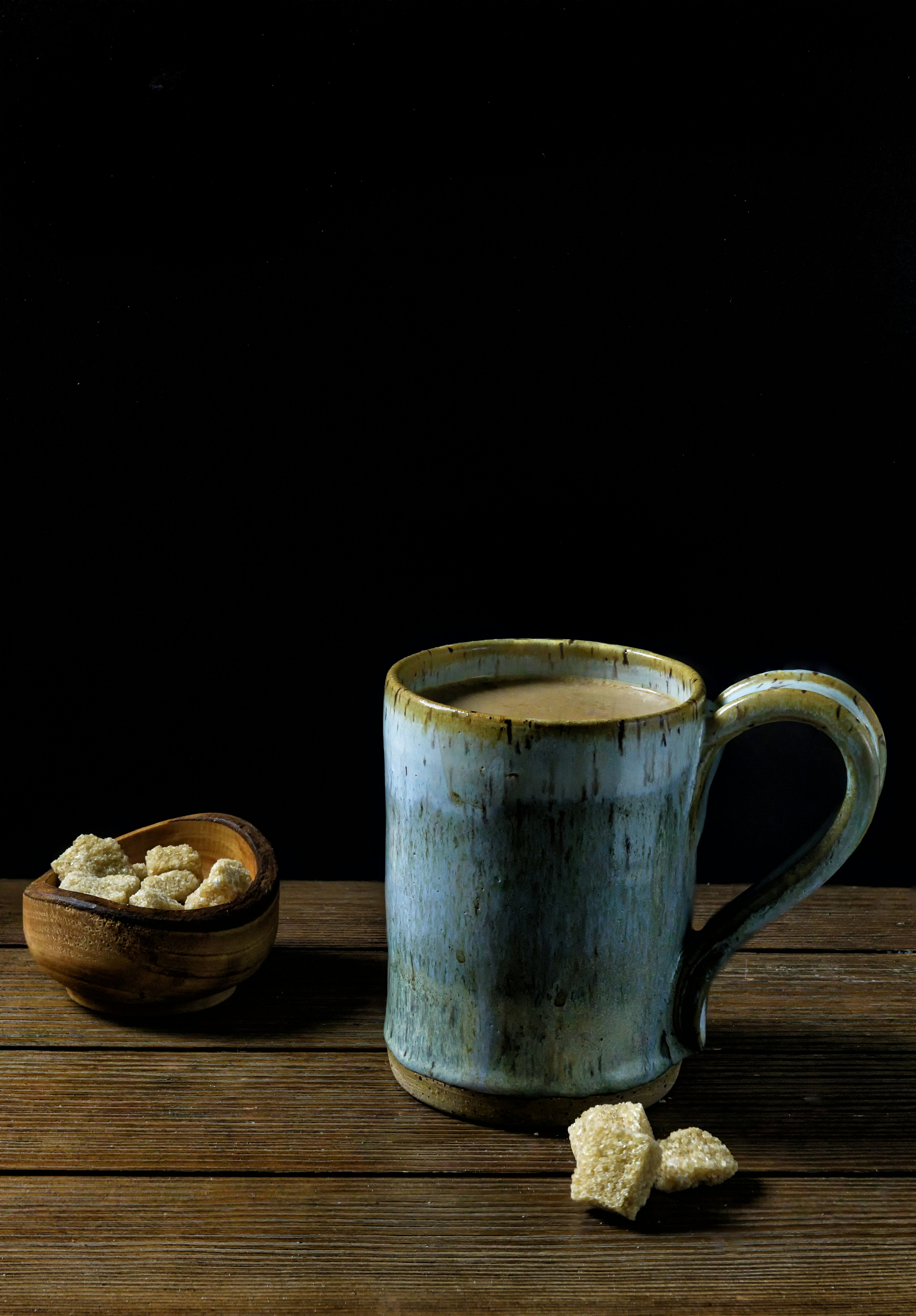 a cup of coffee next to a bowl of sugar cubes