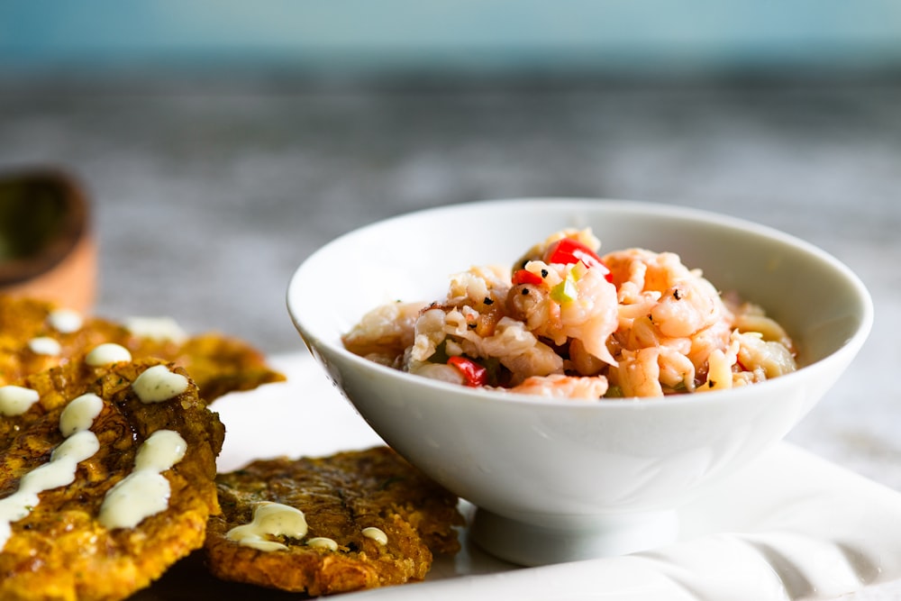 a white bowl filled with food next to two cookies