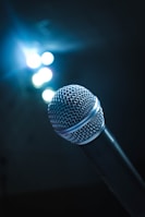 Close-up of a microphone on stage with colorful lights in the background.