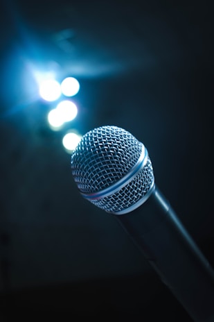 An artistic shot of a microphone surrounded by warm stage lights.