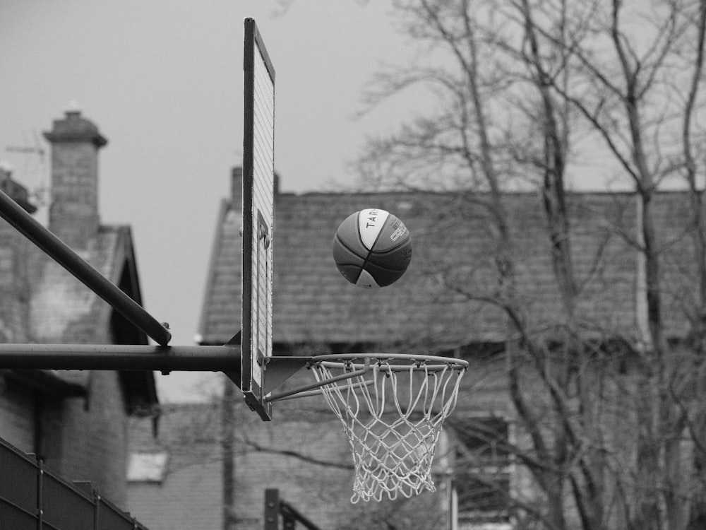 a black and white photo of a basketball going through the hoop