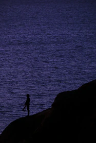 A silhouette of a figure standing on a cliff under a swirling dark blue and purple sky.