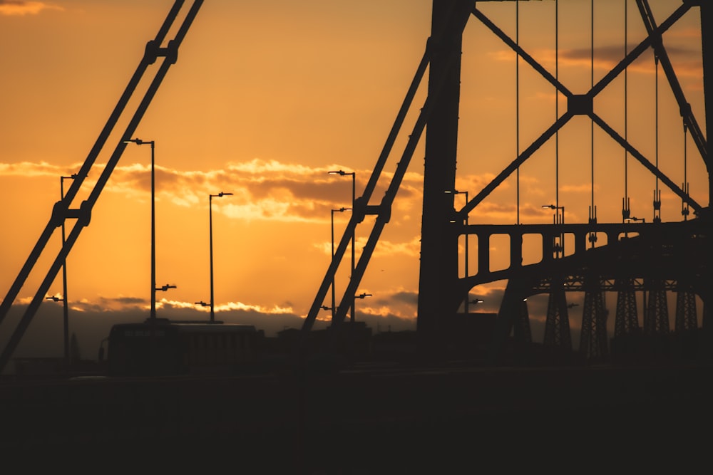 the sun is setting behind a bridge with traffic lights