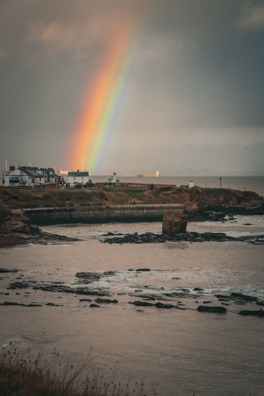 a rainbow shines in the sky over a body of water