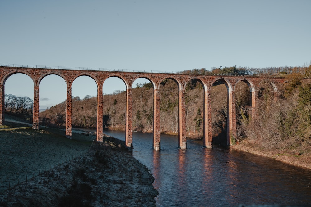 eine Eisenbahnbrücke über einen Fluss mit Bögen