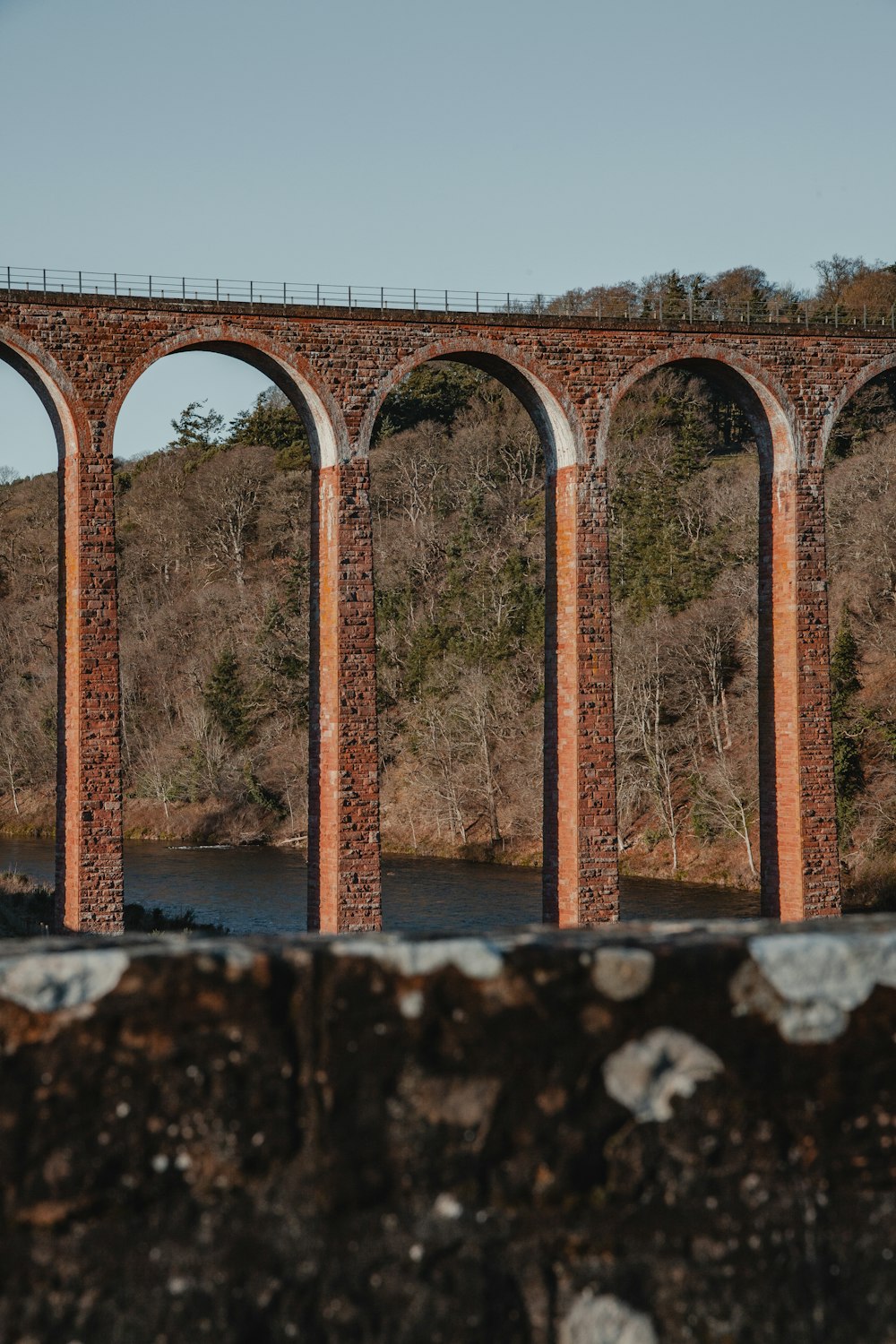 a brick bridge with arches over a body of water