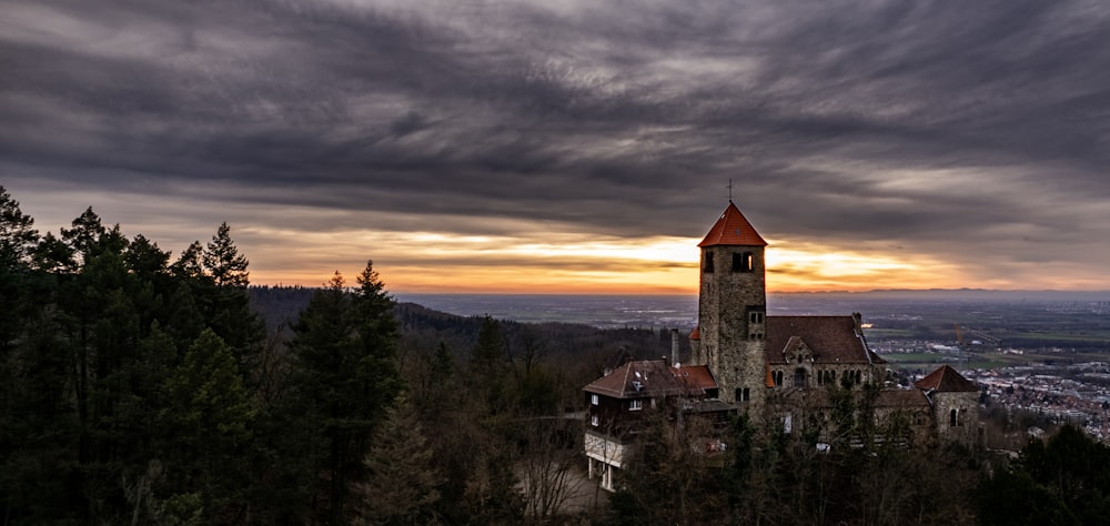 una iglesia en la cima de una colina con una puesta de sol al fondo