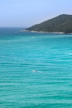 A panoramic view of a turquoise ocean with a small boat drifting near a tropical island.
