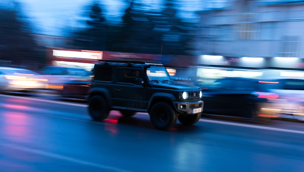 a black jeep driving down a street next to tall buildings