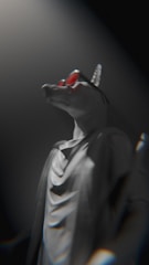 A statue of an anthropomorphic canine figure wearing red sunglasses and a flowing robe. The statue is lit dramatically from above, casting shadows that enhance its authoritative presence.