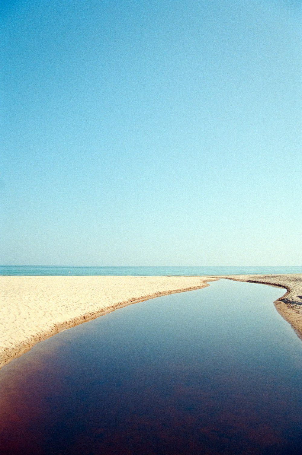 a body of water sitting on top of a sandy beach