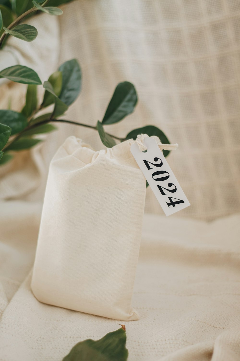 a white bag with a tag on it sitting next to a plant