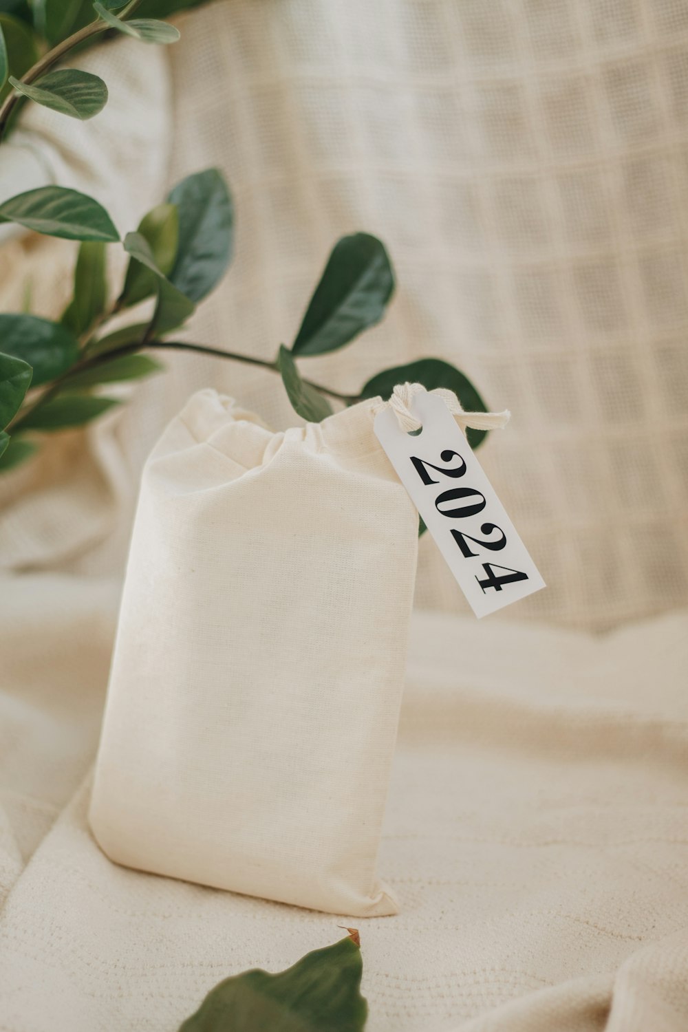 um saco branco com uma etiqueta sentado ao lado de uma planta