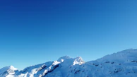 A panoramic view of snow-capped mountains beneath a crystal-clear blue sky.