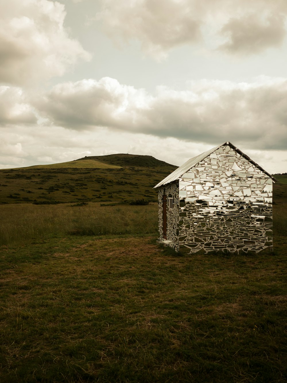 a house made out of rocks in a field