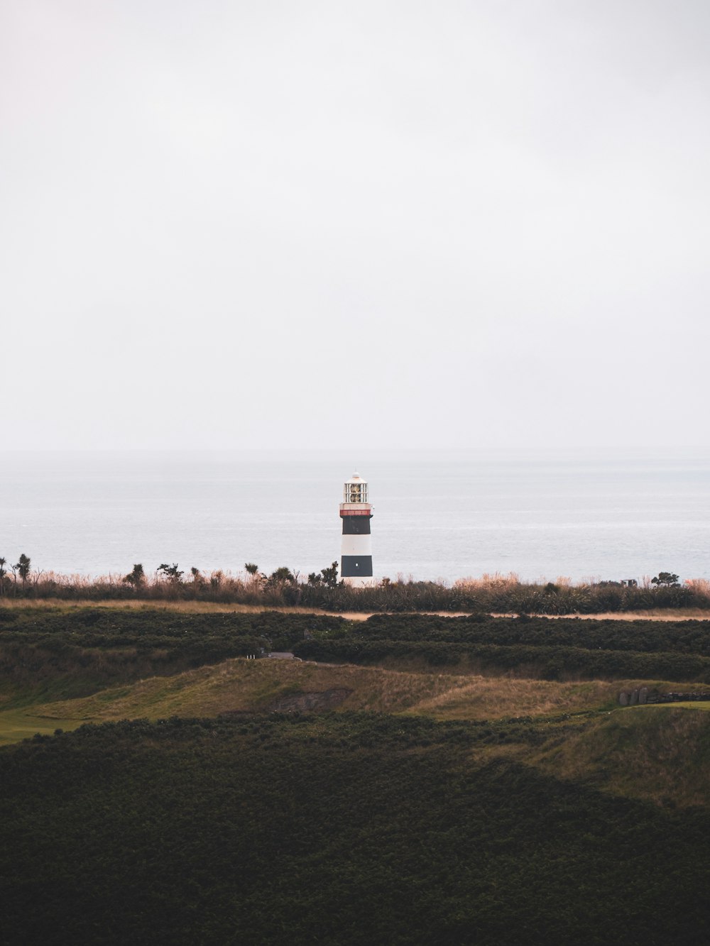 a lighthouse on top of a hill near the ocean