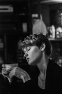 A close-up of a person holding a cup of tea, looking contemplative.