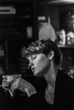 A close-up of a person holding a cup of tea, looking contemplative.