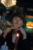 Close-up of a thoughtful person reflecting in a cozy therapy room with books and soft lighting.