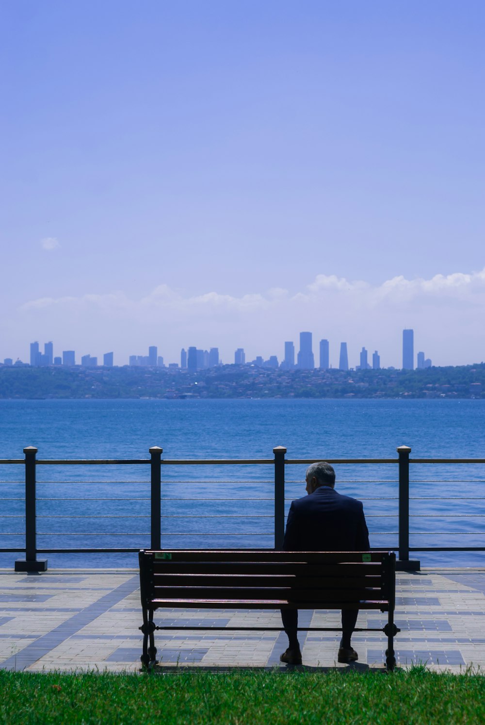 a man sitting on a bench looking out over the water