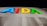 Multicolored letters spelling AIDA are illuminated against a dark background. The letters are vibrant, with blue, red, yellow, and green colors. Below the letters is a section of white material with perforated panels, likely part of a ship or a similar structure.