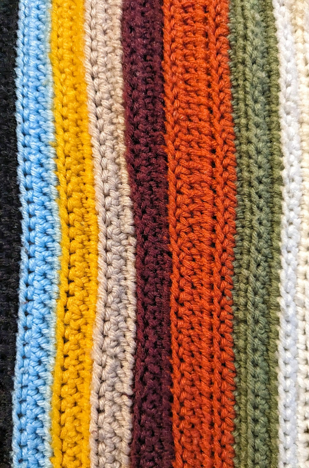 a close up of a crocheted blanket with many colors of yarn