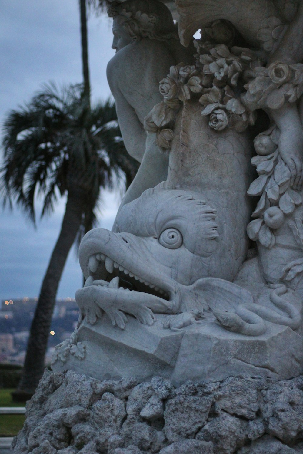 una statua di un drago su una roccia con una palma sullo sfondo