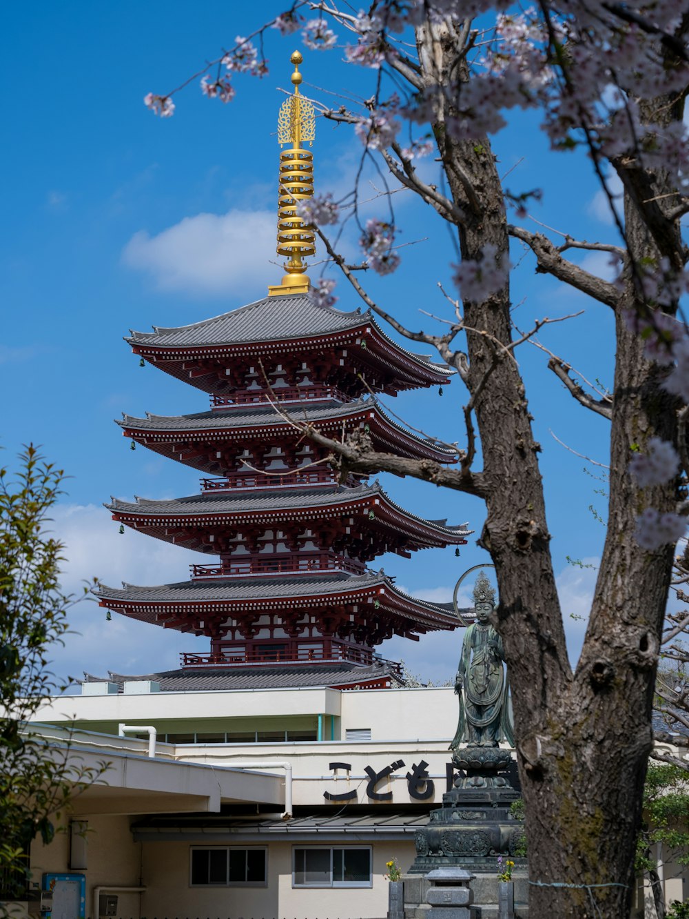 una pagoda alta sentada junto a un árbol frente a un edificio