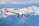 A white commercial airplane with 'SWISS' written in red on the fuselage flies in front of a backdrop of snow-capped mountains. The Swiss flag is visible on the tail fin of the aircraft, and the landing gear is extended as the plane approaches for landing.