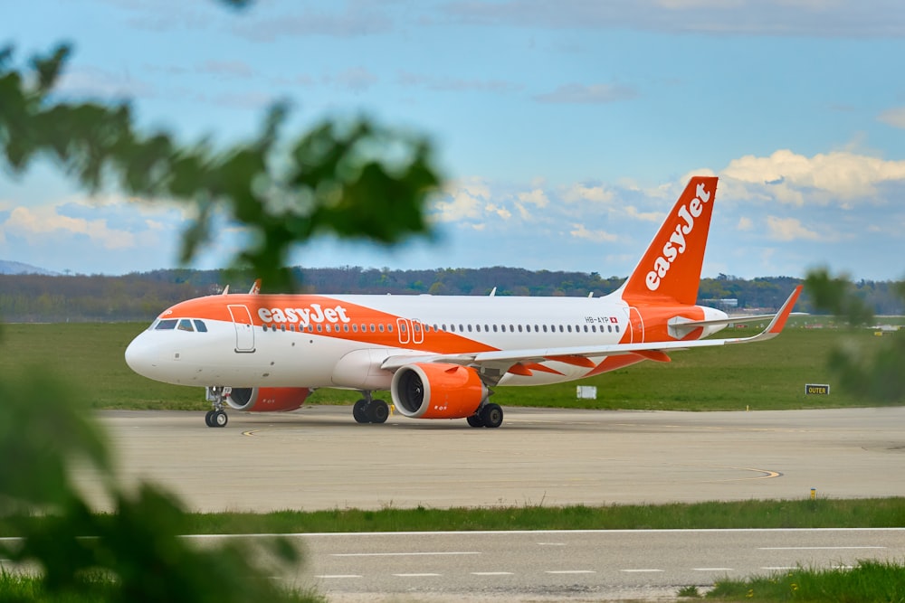 an orange and white jet airliner on a runway