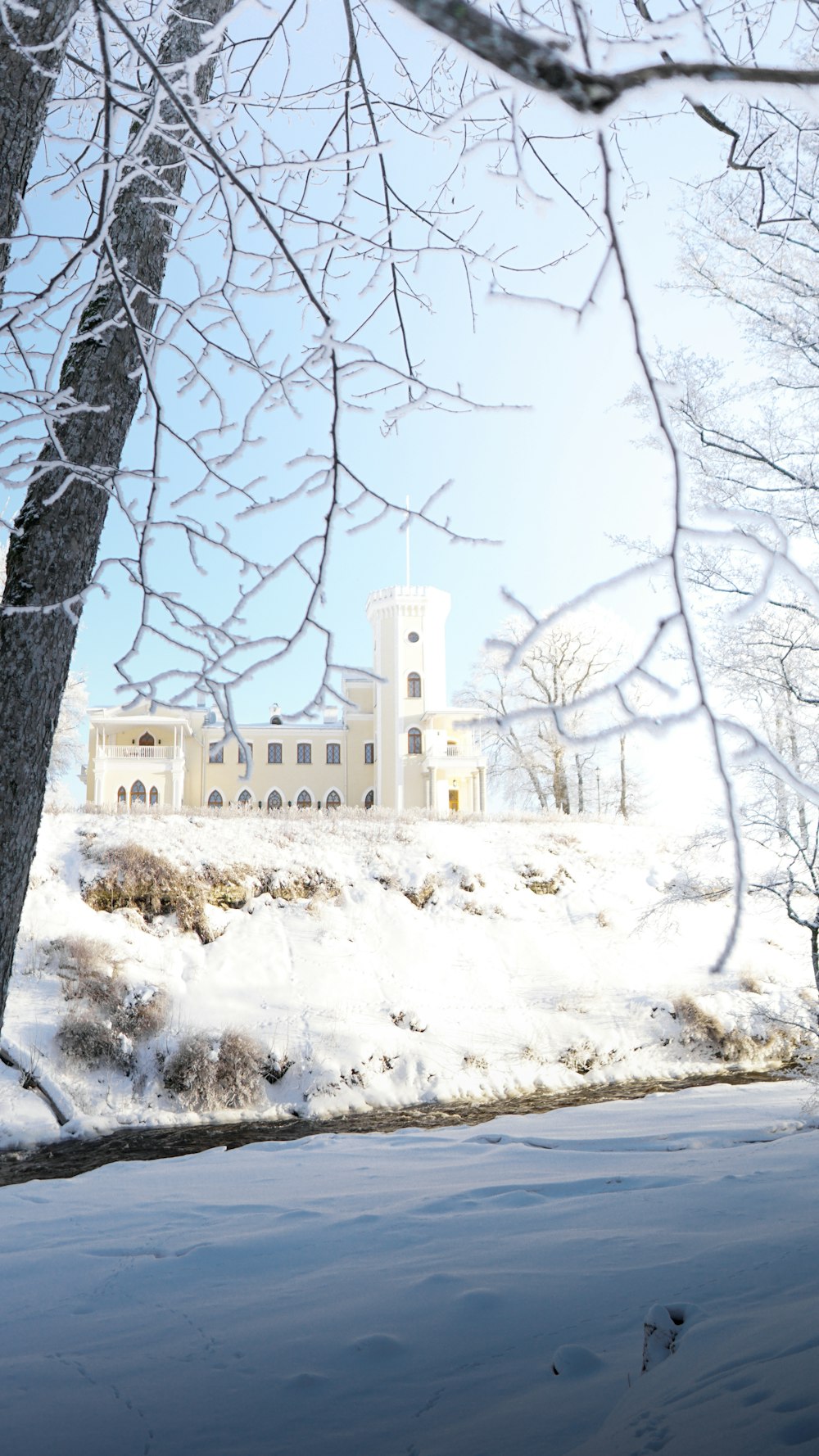 um grande edifício branco sentado no topo de uma colina coberta de neve