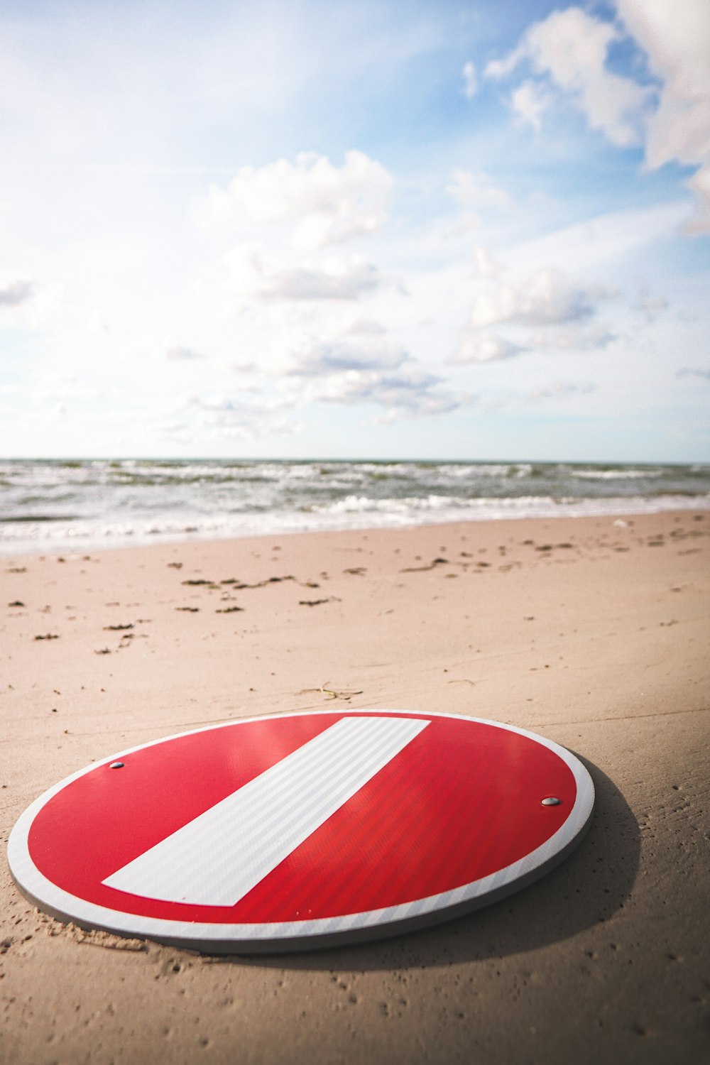 a red and white sign sitting on top of a sandy beach