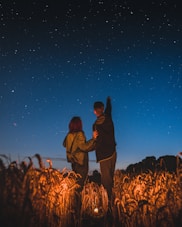 two people standing in a field at night