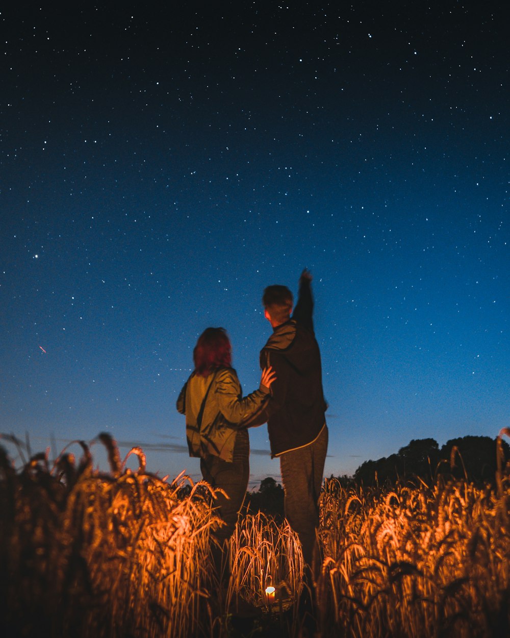 two people standing in a field at night