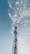 A tall communication tower stands prominently against a sky filled with scattered, fluffy clouds. The structure is composed of lattice-like metal work, rising vertically with various platforms and equipment attached. The overall scene suggests an interplay between technology and nature.
