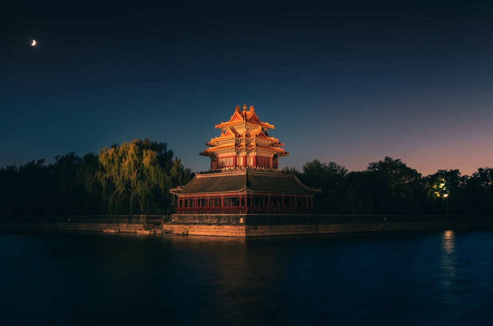 a building sitting on top of a lake next to a forest