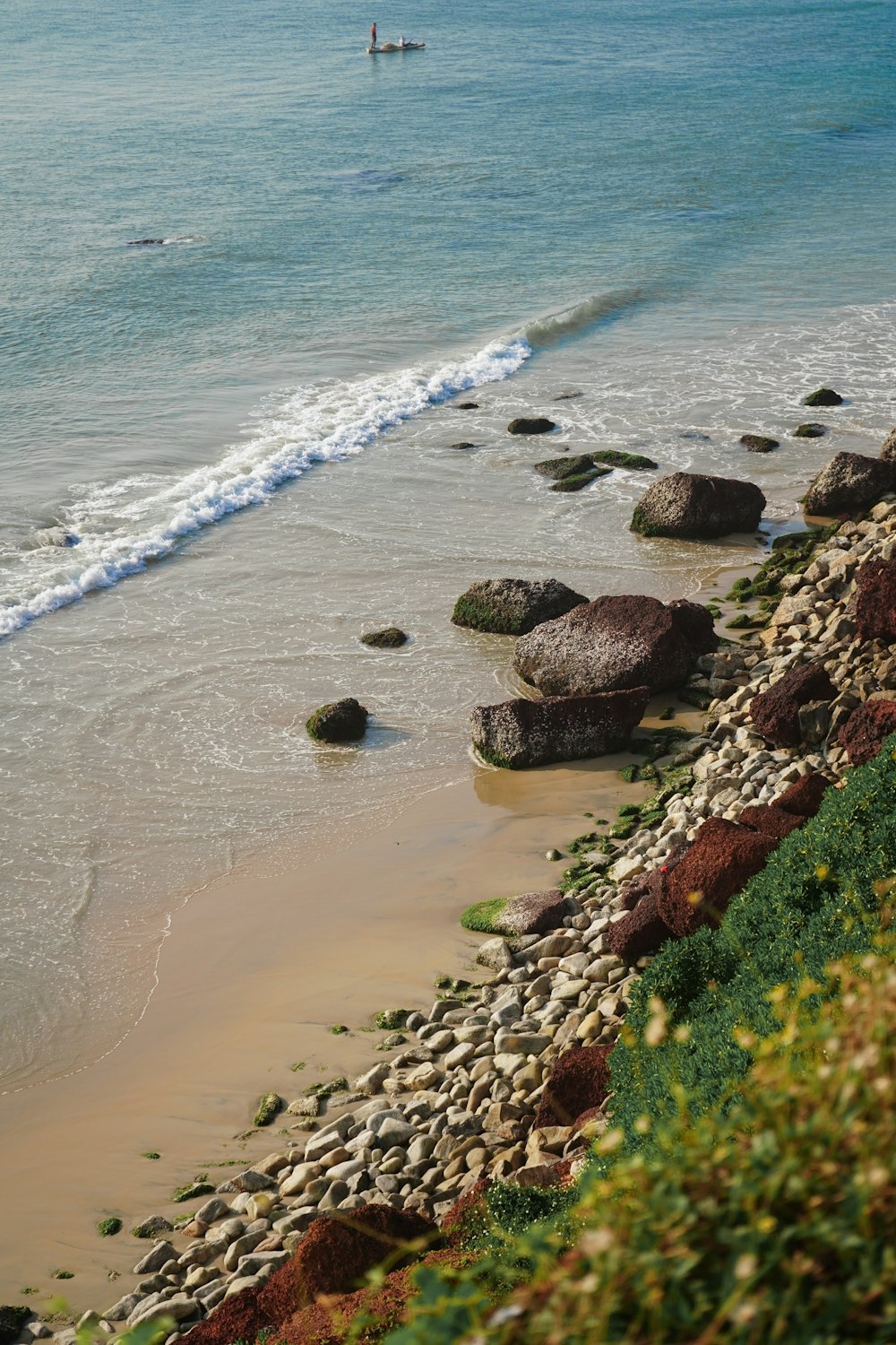 a beach with rocks and a person in the water